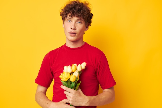 Portrait of a young curly man in a red tshirt a bouquet of flowers holiday gift monochrome shot