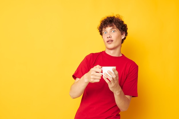 Portrait of a young curly man in a red Tshirt with a white cap in his hands isolated background unaltered