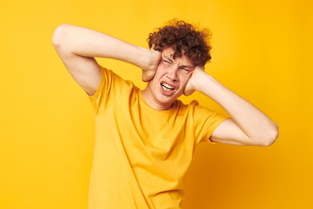 Portrait of a young curly man wearing stylish yellow tshirt posing yellow background unaltered