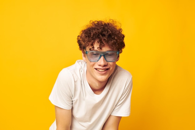 Portrait of a young curly man in a white tshirt blue fashion glasses isolated background unaltered