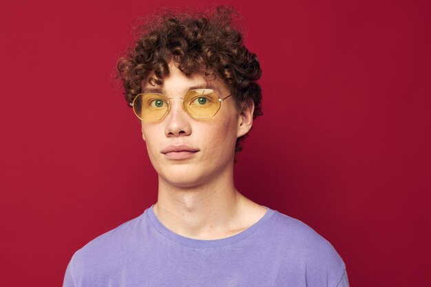 Portrait of a young curly man in yellow glasses purple tshirt emotions Lifestyle