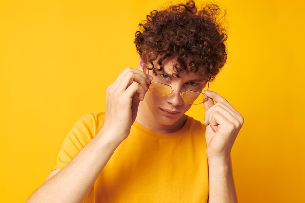 Portrait of a young curly man yellow tshirt glasses fashion hand gestures monochrome shot