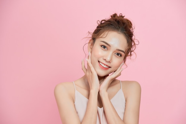 Photo portrait of young cute asian woman smiling over pink background.