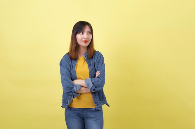 A portrait of a young, cute and athletic Thai Asian girl in a studio against a plain yellow