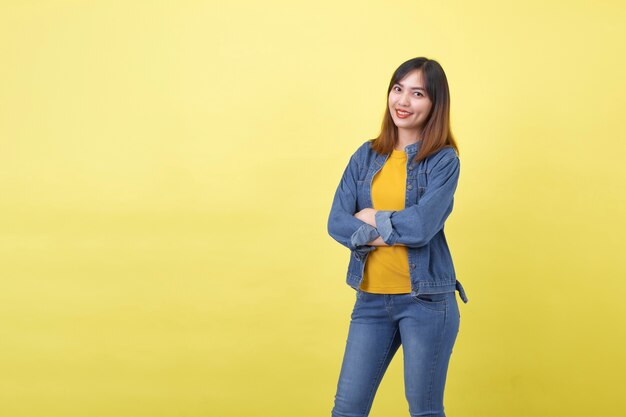 A portrait of a young, cute and athletic Thai Asian girl in a studio against a plain yellow