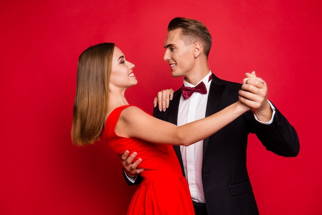赤い背景の上の若いかわいいカップルの肖像画