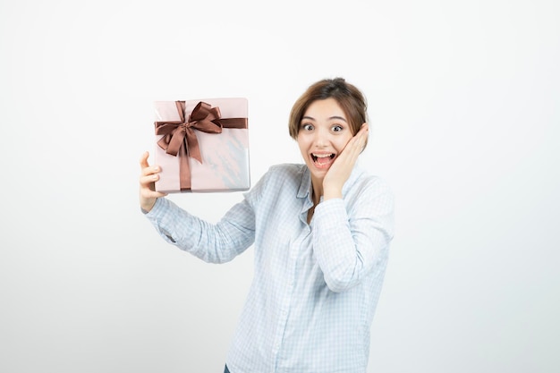 Portrait of a young cute girl holding present box with ribbon. High quality photo