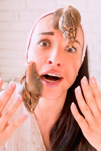 portrait of young dark haired woman with snails achatina giant on her face