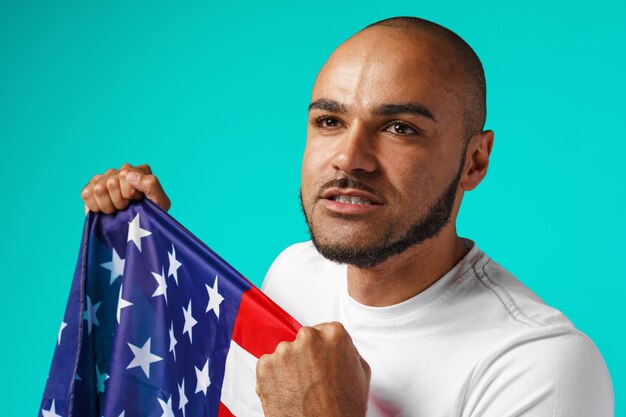 Portrait of young dark-skinned man proudly holding USA flag