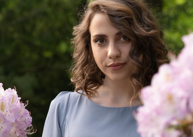 Portrait of a young darkhaired girl on a background of pink flowers Face closeup