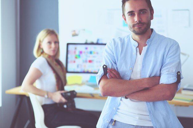 Portrait of young designer in front of laptop and computer while working Assistant using her mobile at background