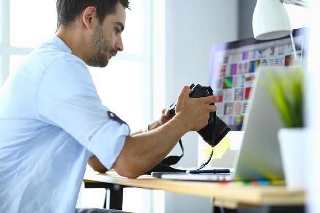 Portrait of young designer sitting at graphic studio in front of laptop and computer while working online