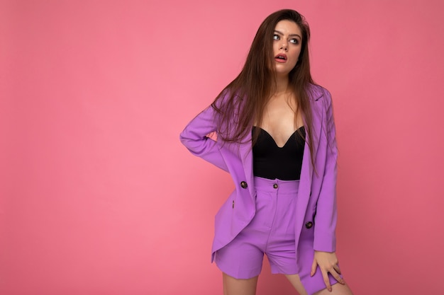 Portrait of young dissatisfied attractive fashionable brunette woman wearing stylish violet suit