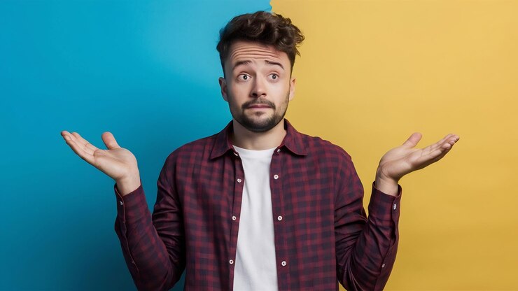 Photo portrait of a young doubtful man shrugging shoulders