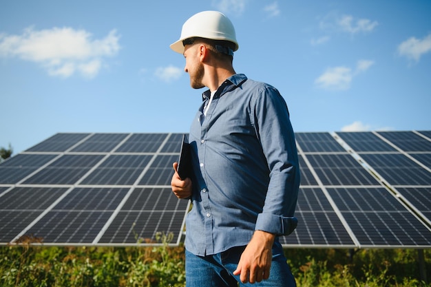 The portrait of a young engineer checks with tablet operation with sun cleanliness on field of photovoltaic solar panels Concept renewable energy technology electricity service green power