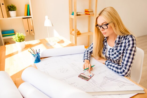 Portrait of young engineer using calculator to end the project