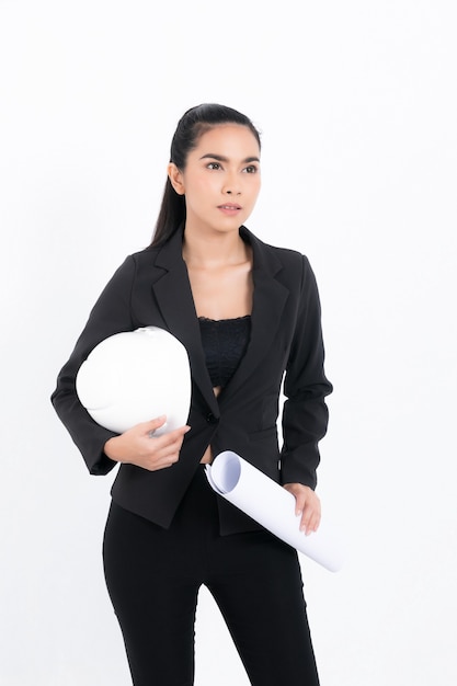 Portrait young engineer woman wearing black suit holding blueprint and white safety-helmet in shot studio isolated on white background.