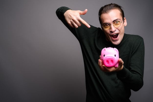 Portrait of young excited man holding piggy bank