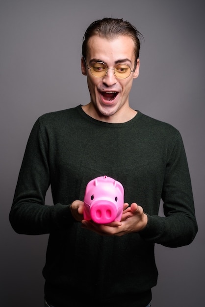 Portrait of young excited man holding piggy bank