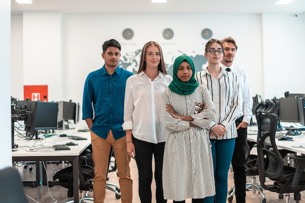 Portrait of young excited multiethnics business team of software developers standing and looking at the camera at modern startup office. High-quality photo