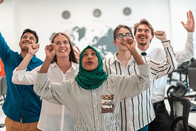 Portrait of young excited multiethnics business team of\
software developers standing and looking at the camera at modern\
startup office. high-quality photo