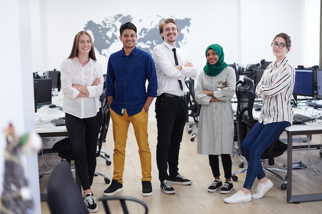 Portrait of young excited multiethnics business team of
software developers standing and looking at camera at modern
startup office