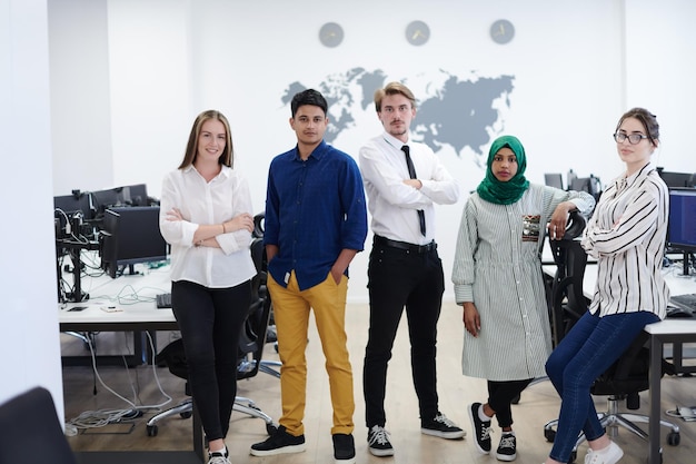 Portrait of young excited multiethnics business team of\
software developers standing and looking at camera at modern\
startup office