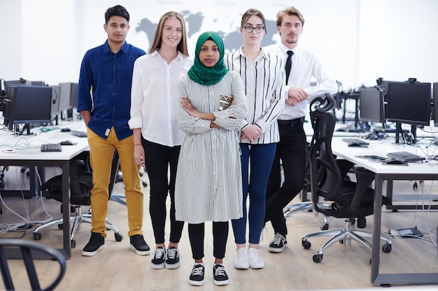 Portrait of young excited multiethnics business team of\
software developers standing and looking at camera at modern\
startup office