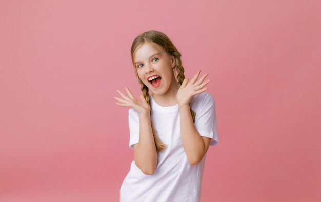 Portrait of young excited shocked smiling girl isolated on pink background