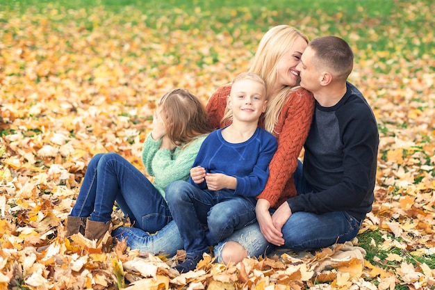 Ritratto di giovane famiglia seduta in foglie d'autunno