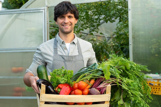 Portrait of a young farmer holding a box of organic vegetables agriculture farm field harvest garden food organic