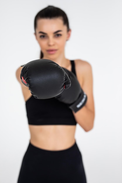 Portrait of a young female boxer punching on white isolated background with copy space