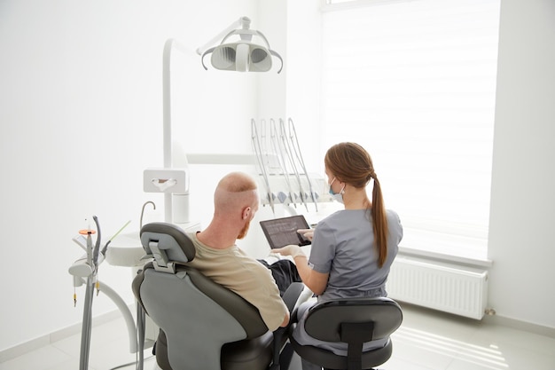 Portrait of young female dentist standing by mid adult man in clinic