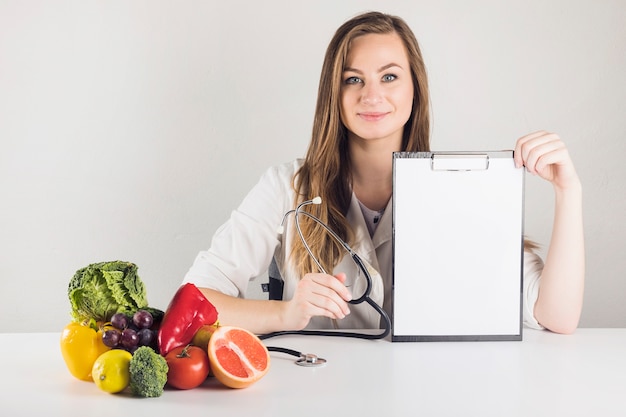 Photo portrait of a young female dietician holding blank clipboard in clinic