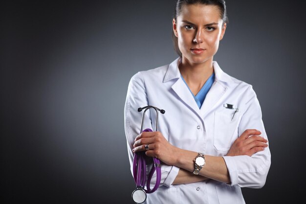 Portrait of young female doctor holding a stethoscope isolated on black background