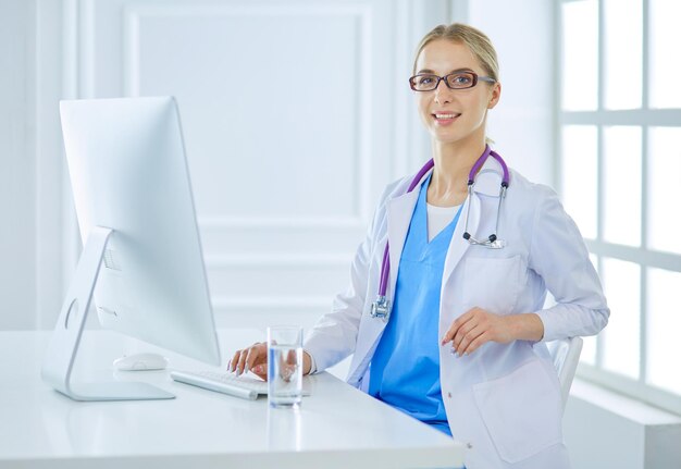 Portrait of young female doctor sitting at desk in hospital