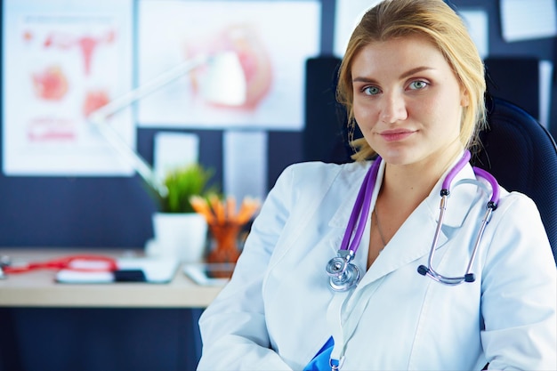 Portrait of young female doctor sitting at desk in hospital