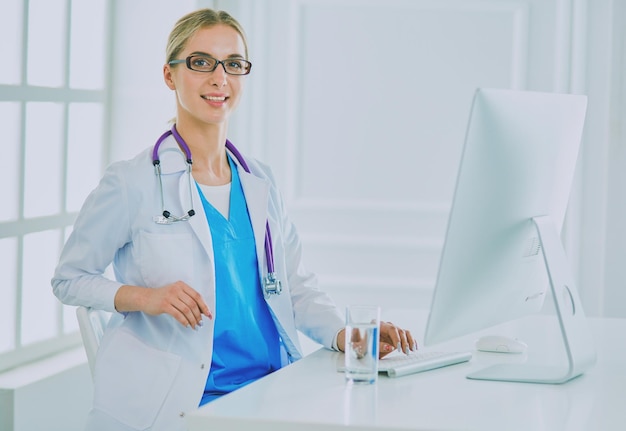 Portrait of young female doctor sitting at desk in hospital