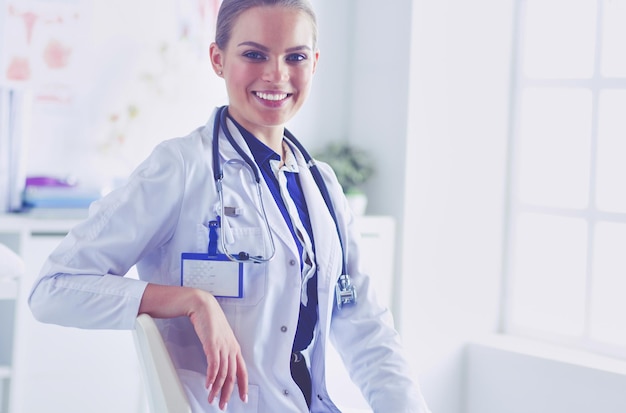 Portrait of young female doctor sitting at desk in hospital