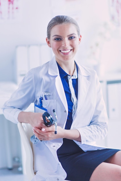 Portrait of young female doctor sitting at desk in hospital