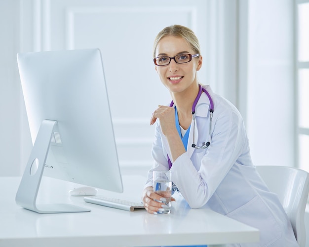 Portrait of young female doctor sitting at desk in hospital