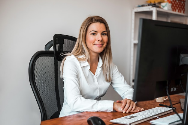  Portrait of a young female entrepreneur sitting at a desk in her home office. Looking at camera. 