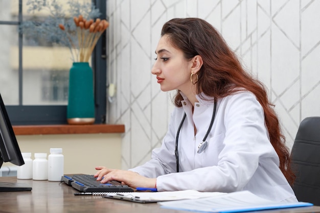 Portrait of young female health care worker sitting at the office and working on the pc High quality photo