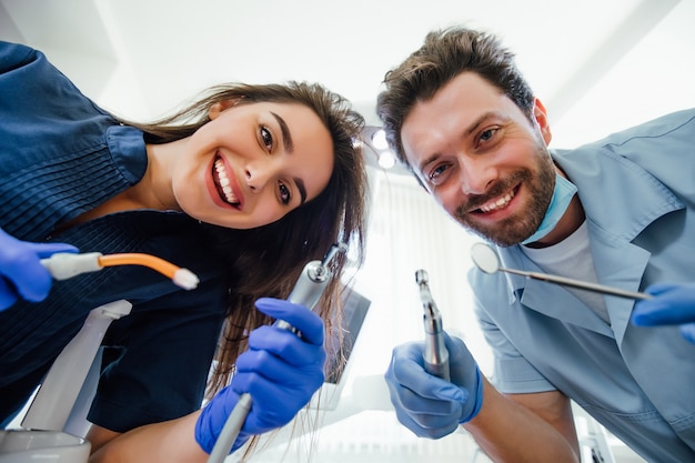 Photo portrait of a young female nurse and dentist doctor wearing a blue coat posing in a dentist office with medical equipment.