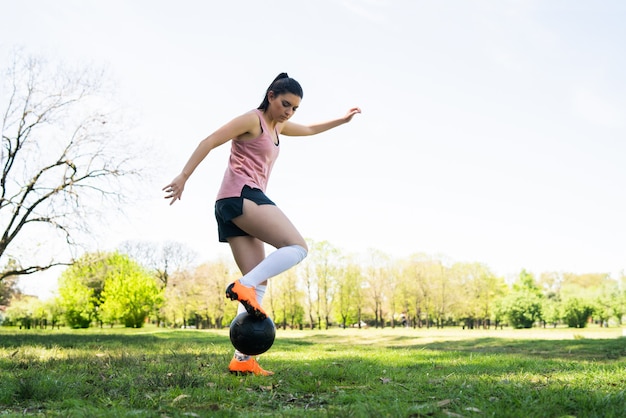 フィールドでボールを練習しながらコーンの周りを走っている若い女性サッカー選手の肖像画。スポーツの概念。