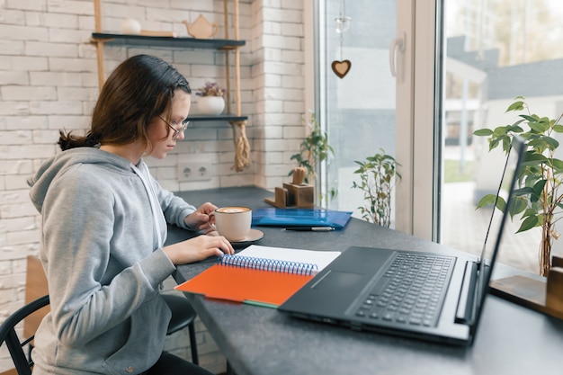 Portrait of young female student in coffee shop with laptop