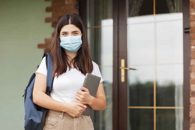 Ritratto di una giovane studentessa con maschera e tablet