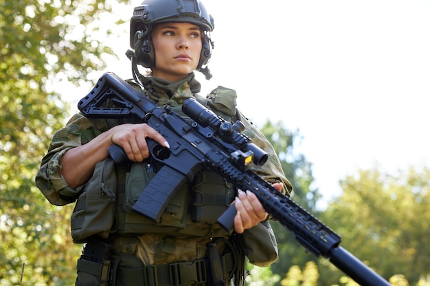 Portrait of young female with weapon in military wear outdoors