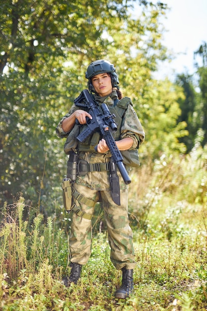 Portrait of young female with weapon in military wear outdoors