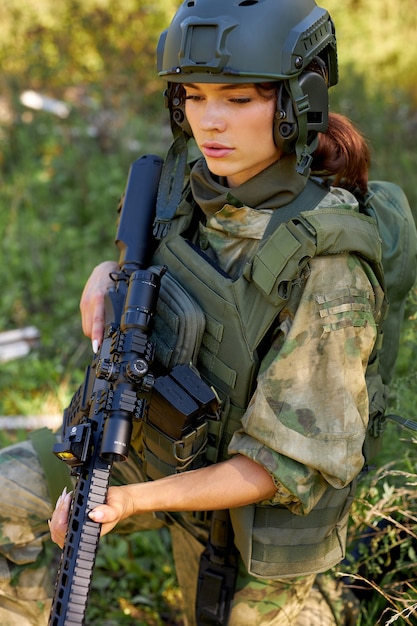 Portrait of young female with weapon in military wear outdoors